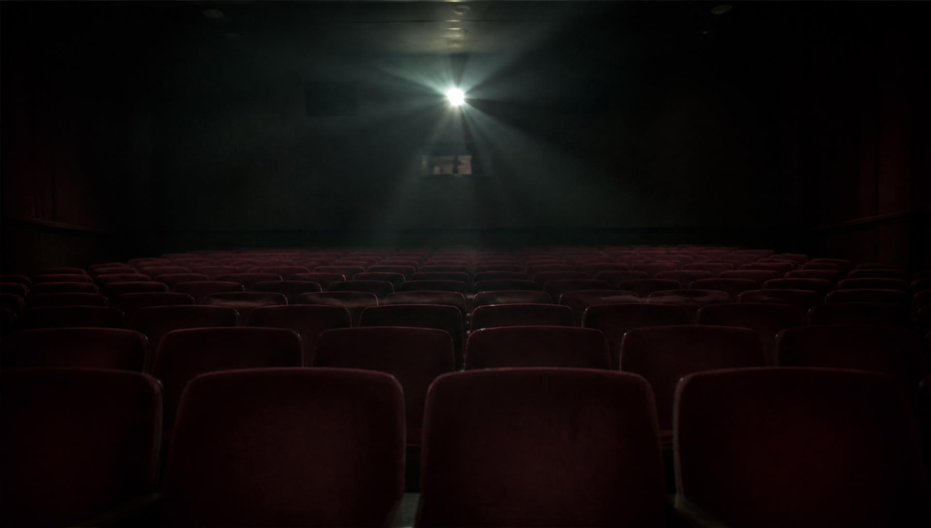 Empty cinema auditorium lit only by the projector beam