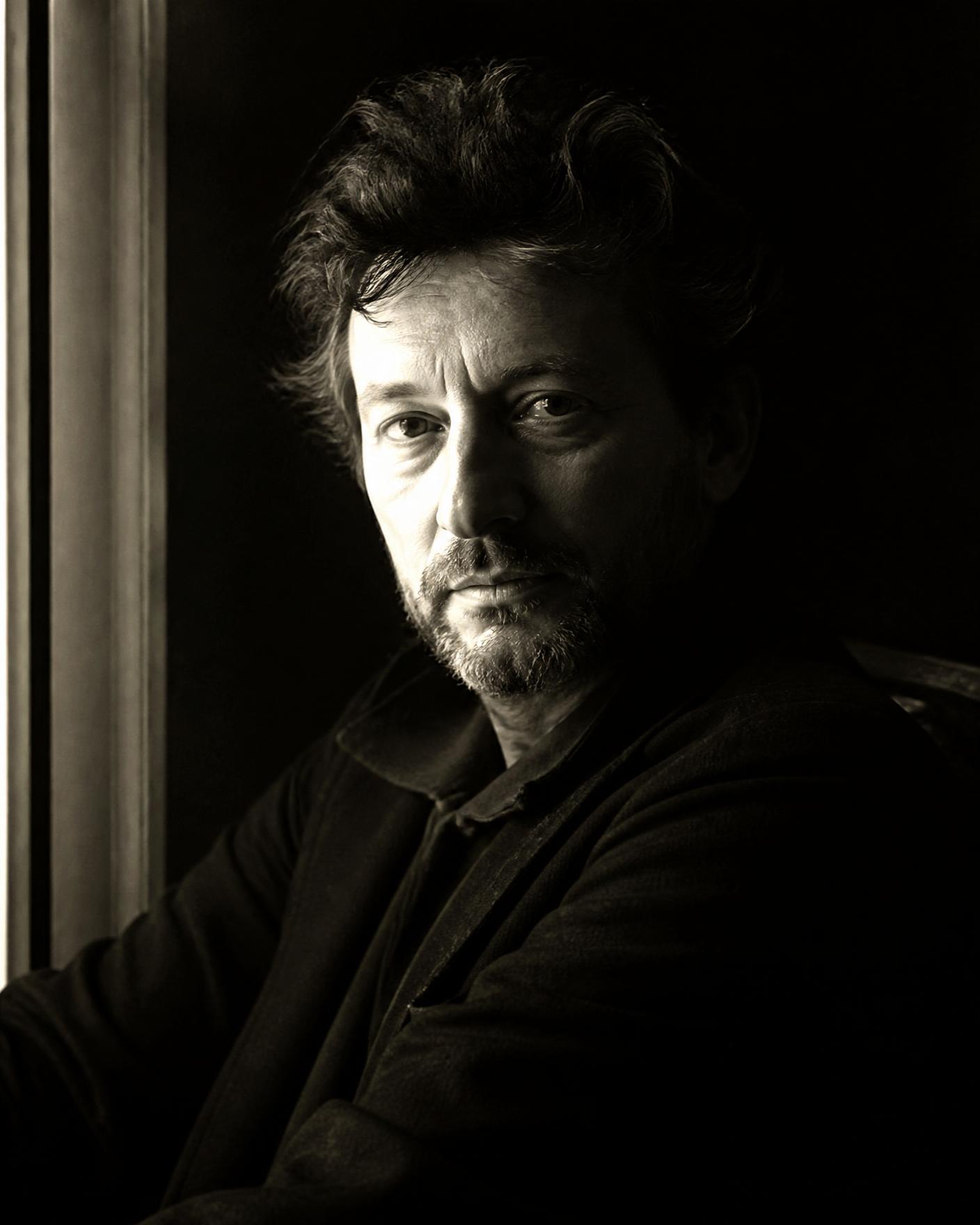 Portrait of a director sitting in shadow beside a window