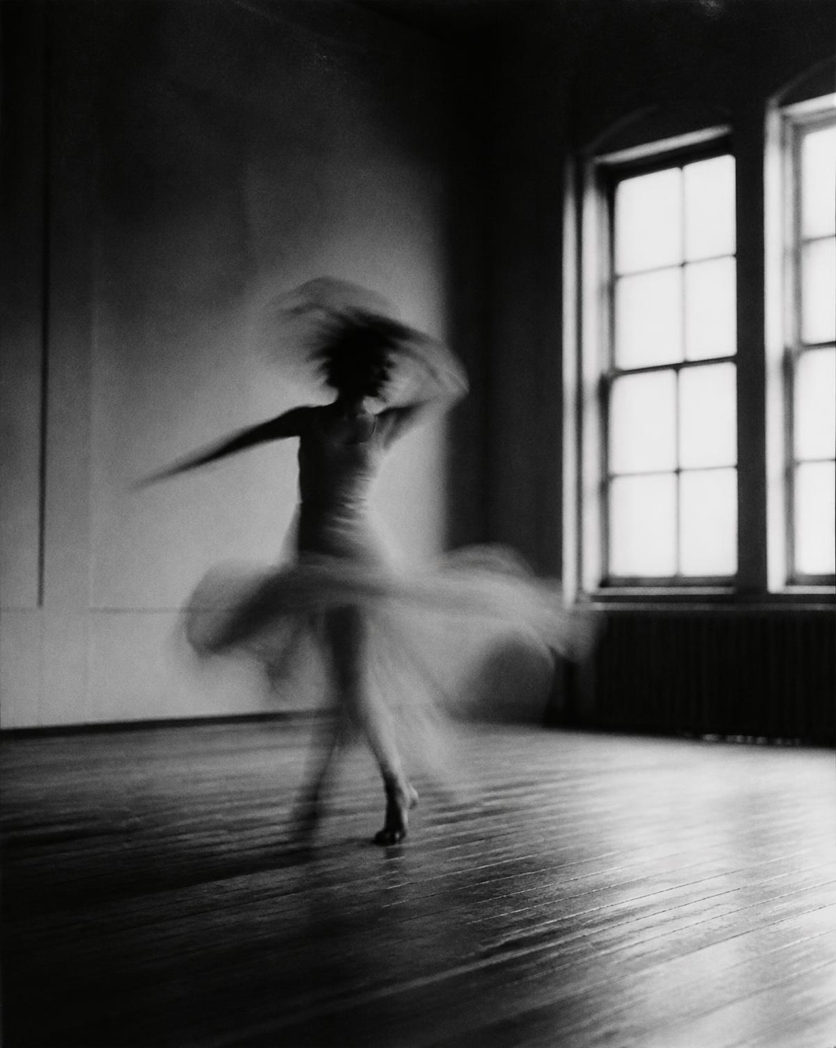 A dancer turning in an empty rehearsal room, captured in long exposure